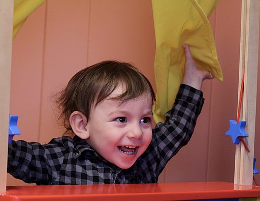 Toddler boy playing in a puppet theatre in the Discovery Kids room at Celebration Community Church.
